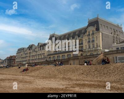 Cabourg, France, 2021 mars : Grand Hôtel à Cabourg jour du printemps, vue sur le bâtiment depuis la mer, touristes assis sur le sable, repos, détente Banque D'Images