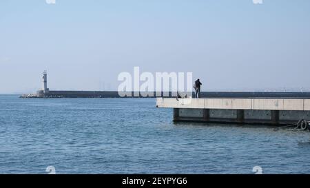 istanbul kadikoy personnes pêchant sur la rive en béton et petit et vieux bateau de pêche d'époque sur bosporus istanbul près de la gare centrale de haydarpasa. Banque D'Images