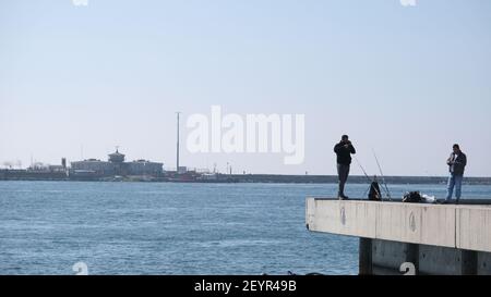 istanbul kadikoy personnes pêchant sur la rive en béton et petit et vieux bateau de pêche d'époque sur bosporus istanbul près de la gare centrale de haydarpasa. Banque D'Images