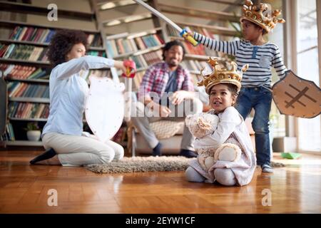 Maman et son fils hurle et jouent avec des épées à la maison tout en ayant un bon moment dans une atmosphère gaie avec la famille. Famille, ensemble, amour, pla Banque D'Images