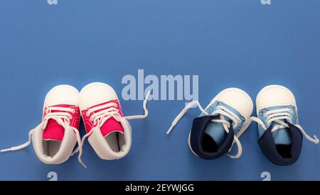 Chaussures de sport pour enfants sur fond bleu. Baskets rouges et bleues pour bébé de petite taille, chaussons en toile, vue du dessus. Espace pour le texte, le modèle Banque D'Images