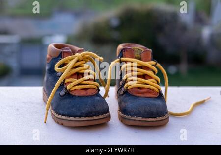 Chaussons bébé chaussures bleu jaune couleur sur sol blanc, flou nature arrière-plan. Baskets enfant de petite taille à l'extérieur, sur le terrain de jeu, enfant actif Banque D'Images