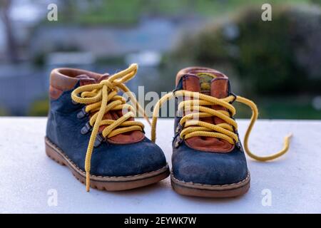 Chaussons bébé chaussures bleu jaune couleur sur sol blanc, flou nature arrière-plan. Baskets enfant de petite taille à l'extérieur, sur le terrain de jeu, enfant actif Banque D'Images