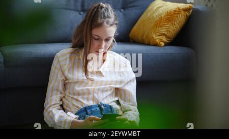 Tween fille avec smartphone à la maison. Banque D'Images