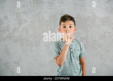 Petit garçon avec son doigt levé pour se muer pour un endroit calme. Banque D'Images