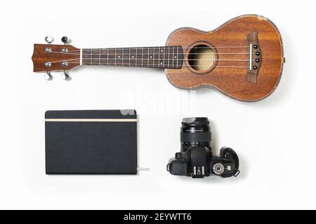 Un kit de voyage musical : ukulele, un agenda de voyage et un appareil photo isolés sur fond blanc Banque D'Images