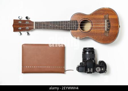 Un kit de voyage musical : ukulele, un agenda de voyage et un appareil photo isolés sur fond blanc Banque D'Images