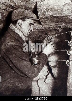 Une ancienne photographie (vers les années 1940) montrant l'agent de sécurité américain qui vérifie les lignes de communication souterraines dans une mine de charbon. Banque D'Images