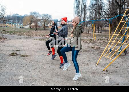 Cours de fitness en groupe à l'extérieur. Cours de gym organisés dans les parcs publics. Trois femmes et hommes s'entraîner ensemble dans le parc public. Santé Banque D'Images