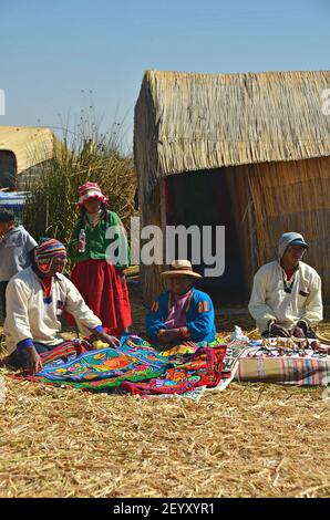 Peuple indigène Uru sur une île flottante à l'auto-mode vendant leurs objets d'artisanat devant leur maison sur le lac Titicaca au Pérou Puno. Banque D'Images