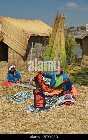 Peuple indigène Uru sur une île flottante à l'auto-mode vendant leurs objets d'artisanat devant leur maison sur le lac Titicaca au Pérou Puno. Banque D'Images