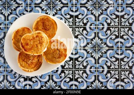 Pâtisserie portugaise traditionnelle appelée Queijada de Sintra sur fond de tuiles portugaises. Vue de dessus avec espace de copie Banque D'Images