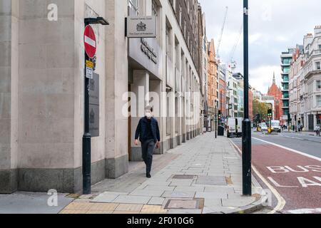 LONDRES, ANGLETERRE - 23 OCTOBRE 2020: Homme portant un masque de visage marchant devant le tribunal central de la famille, registre principal de la Division de la famille du Th Banque D'Images