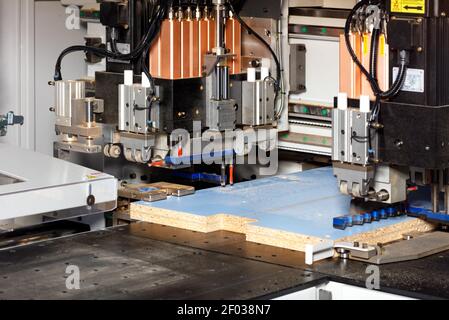 Ligne pneumatique d'une perceuse et d'une fraiseuse automatiques dans le processus de fabrication de meubles d'armoire à partir de panneaux de particules. Banque D'Images