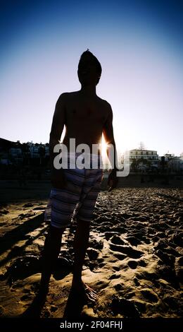 Photo verticale d'une personne se tenant sur la plage au coucher du soleil à Cascais, Portugal Banque D'Images