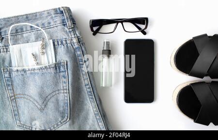 pose à plat des objets et accessoires pour femmes sur fond blanc. Jeans, lunettes, masque médical. Banque D'Images