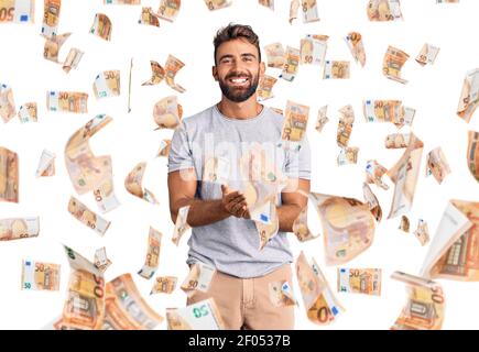 Jeune hispanique portant des vêtements décontractés souriant avec les mains paumes ensemble recevoir ou donner des gestes. Tenir et protection Banque D'Images