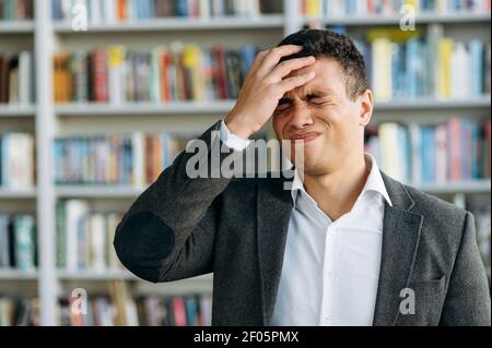 Portrait de la déception hispanique gars dans l'habillement formel, échec de l'affaire importante ou a obtenu une mauvaise nouvelle. Un jeune homme frustré couvrant son visage et ses yeux avec sa main Banque D'Images
