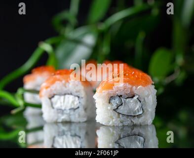 Cuisine japonaise Sushi Roll avec fromage de Philadelphie à l'intérieur sur fond noir miroir. Menu du restaurant, bar à sushis Banque D'Images