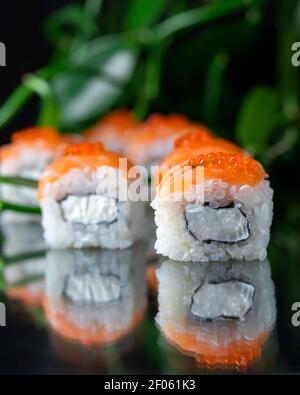 Cuisine japonaise Sushi Roll avec fromage de Philadelphie à l'intérieur sur fond noir miroir. Menu du restaurant, bar à sushis Banque D'Images