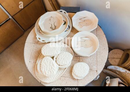 De dessus de vaisselle assortis en argile placée dessus table ronde dans un atelier de poterie Banque D'Images