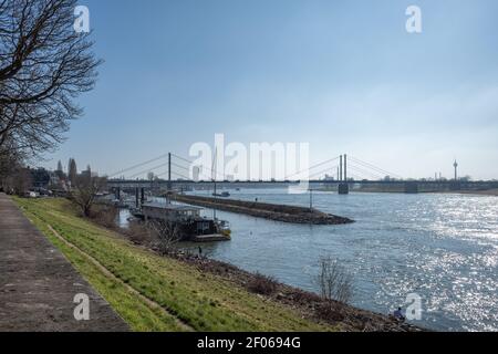 Vue extérieure ensoleillée le long de la promenade au bord de la rivière, de la jetée et du port sur le Rhin et paysage urbain, pont suspendu et tour du Rhin. Banque D'Images