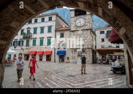 Vue sur la place principale et la vieille tour de l'horloge depuis le dessous de l'arcade de la porte de la mer menant à la vieille ville de Kotor. Banque D'Images