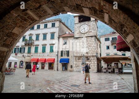 Vue sur la place principale et la vieille tour de l'horloge depuis le dessous de l'arcade de la porte de la mer menant à la vieille ville de Kotor. Banque D'Images