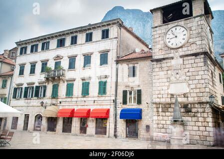 Vue sur la place principale et la vieille tour de l'horloge depuis le dessous de l'arcade de la porte de la mer menant à la vieille ville de Kotor. Banque D'Images