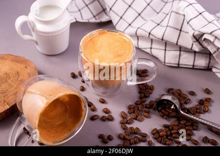 Café Dalgona. Boisson fouettée à glacer avec café instantané populaire en Corée cocktail crémeux dans une tasse en verre transparent à double paroi contre le dos gris Banque D'Images