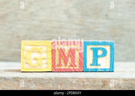 Bloc alphabétique de couleur dans le mot GMP (Abréviation de bonne pratique de fabrication) sur fond de bois Banque D'Images
