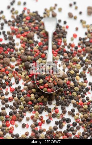 Mélange de grains de poivre et de cuillère sur fond blanc Banque D'Images