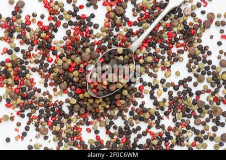 Mélange de grains de poivre et de cuillère sur fond blanc Banque D'Images