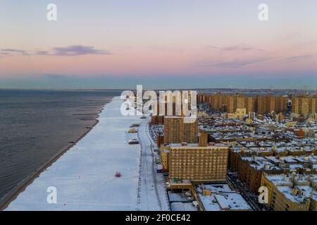 Vue aérienne d'une plage enneigée de Coney Island Beach pendant l'hiver au lever du soleil à Brooklyn, New York. Banque D'Images