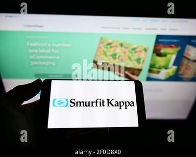 Personne tenant un téléphone portable avec le logo d'entreprise de la société irlandaise d'emballage Smurfit Kappa Group plc à l'écran devant la page Web. Mise au point sur l'affichage du téléphone. Banque D'Images