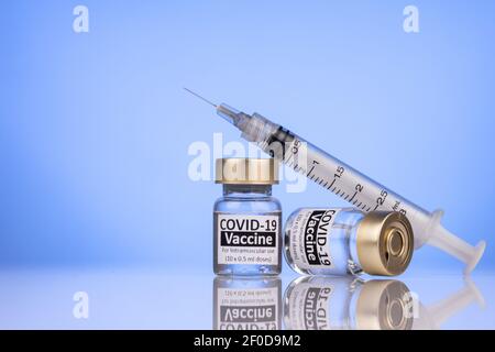 Seringue reposant sur des flacons de vaccin Covid-19 concept avec surface réfléchissante Banque D'Images