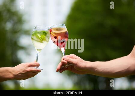 Hand holding cocktail verres trinquer ensemble à l'extérieur. Banque D'Images