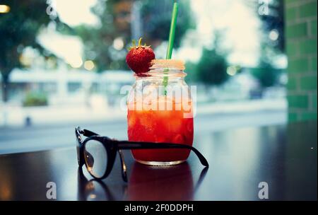 verre avec une boisson dans la main d'une femme et un café Banque D'Images