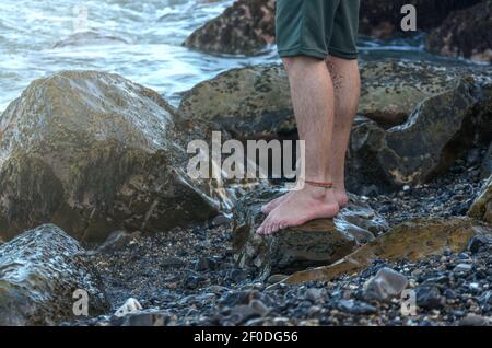 Homme jambes sur la côte de la plage de rochers Banque D'Images