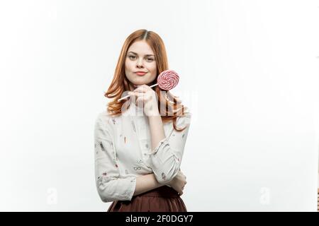 jolie femme aux cheveux rouges avec des sucettes multicolores dans ses mains joie bonbons Banque D'Images