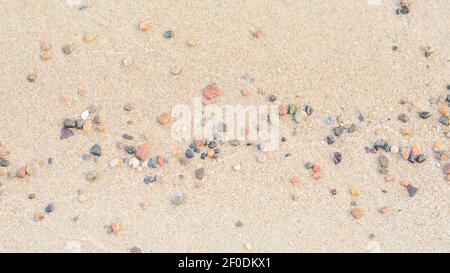 Petites pierres de galets sur un rivage sableux humide. Grand format, paysage panoramique. Mise au point sélective, espace de copie. Banque D'Images