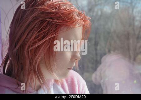 Une adolescente aux cheveux rouges donne sur la rue. Des émotions tristes sur le visage. Gros plan, mise au point sélective. Banque D'Images