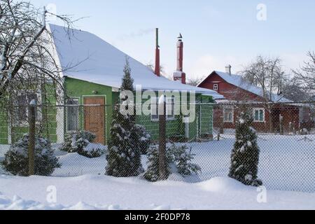 La cour couverte de neige de la maison en bois dans le village biélorusse. Ancienne maison de campagne en hiver Banque D'Images