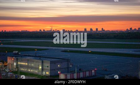 L'aérodrome et la piste de l'aéroport international de Pulkovo à Saint-Pétersbourg, en Russie, avec le beau coucher de soleil qui peint le ciel au-dessus de la ville silhouettée Banque D'Images