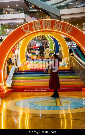 Une femme d’âge moyen prend un selfie devant un tunnel coloré pour la Journée des femmes dans le Super Brand Mall de Shanghai à Lujiazui, dans le district de Pudong, en Chine Banque D'Images