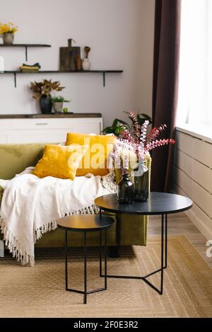 Un canapé vert avec des oreillers jaunes et un double noir Table basse et couverture dans une vie moderne de style scandinave intérieur de la chambre Banque D'Images