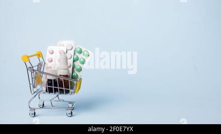 Médicaments et pilules dans un panier sur fond bleu. Administration de médicaments. Copier l'espace Banque D'Images