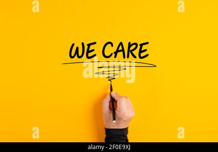 Main masculine écrivant le message nous nous soucions sur fond jaune. Concept de service client. Banque D'Images
