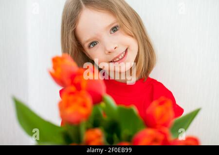 Belle fille dans un col de cygne rouge vif tenant un bouquet de tulipes rouges Banque D'Images