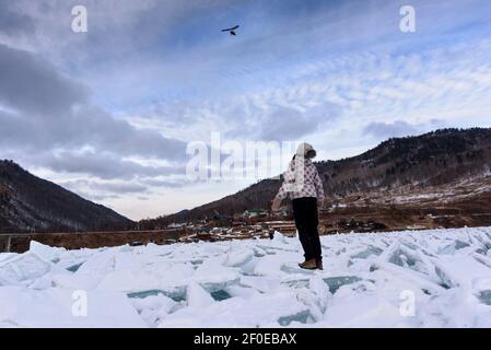 Silhouette de fille vue de dos vers le haut du ciel sur un parapente volant reste sur une pile de belle Des buttes de glace près de l'ancien chemin de fer Circum Baikal Banque D'Images